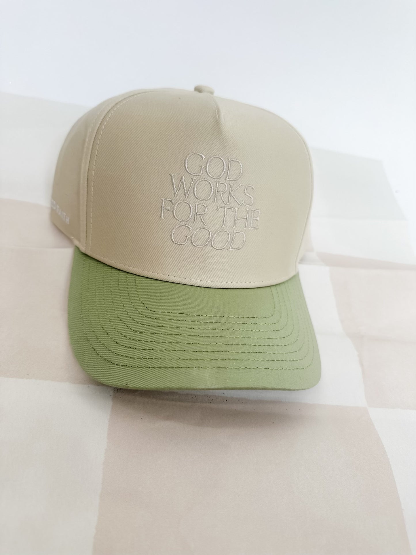 God Works for the Good Trucker Hat